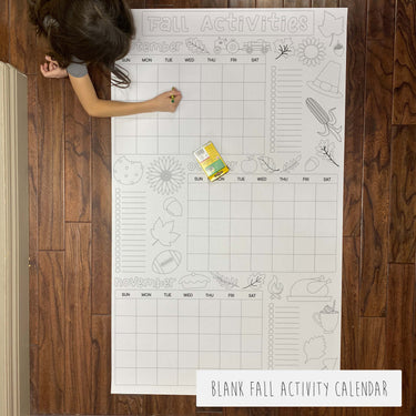Blank fall activity calendar on a wooden floor with a child interacting with it.